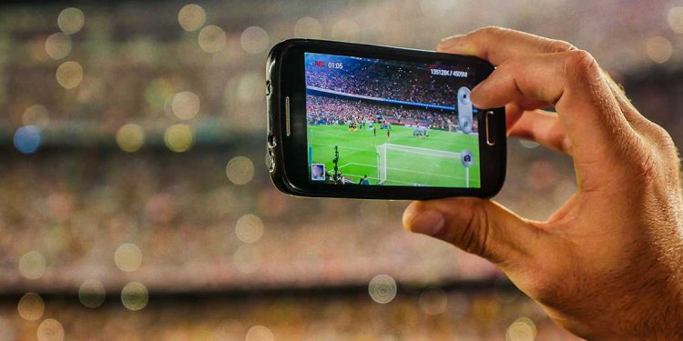 Holding mobile phone to take photo in stadium