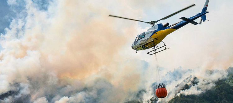 helicopter flying over wildfire smoke