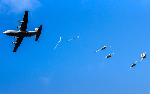 Military transport aircraft and airborne troops during military freefall operations.